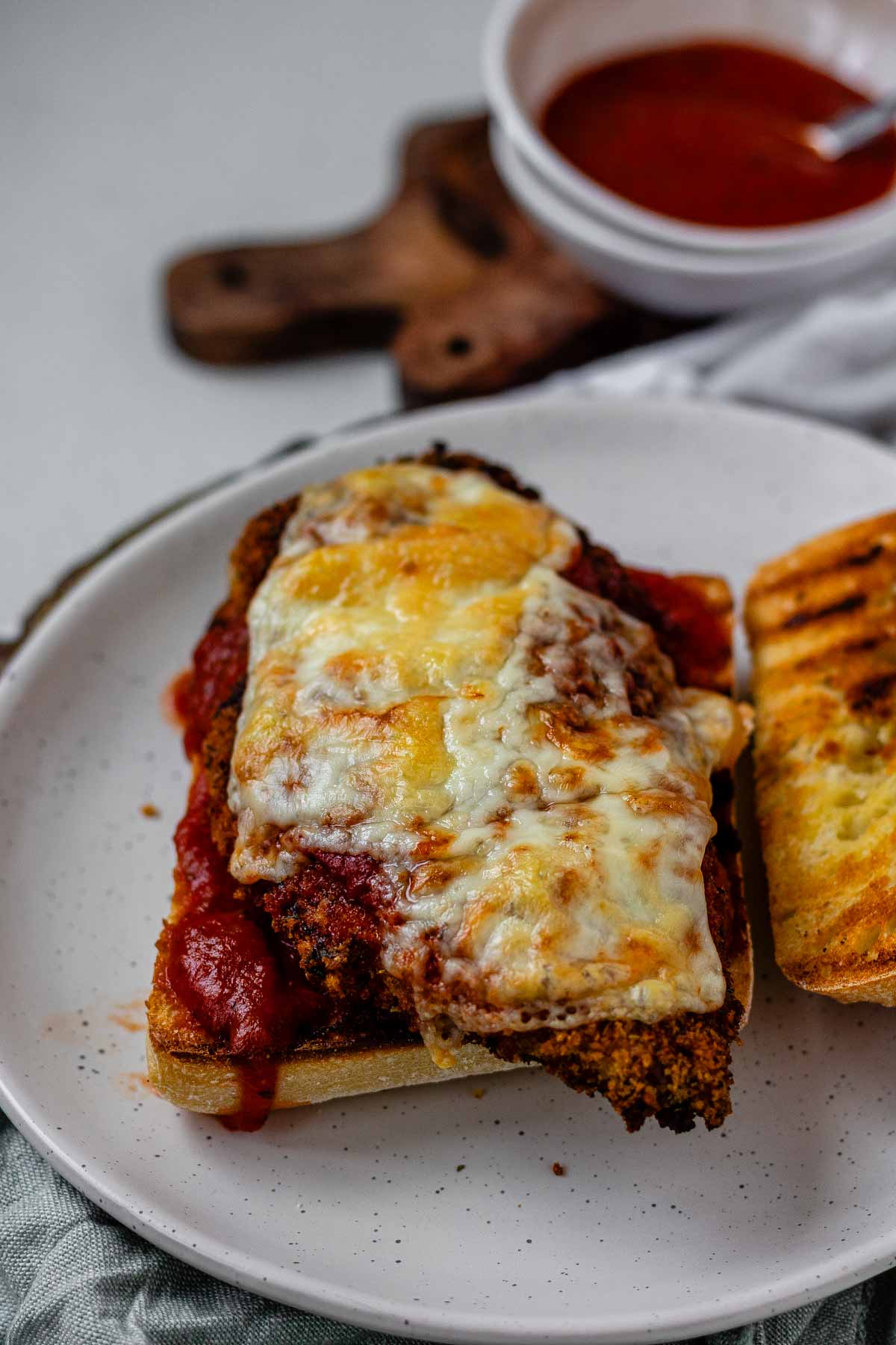 An open sandwich with breaded chicken, red sauce, and melted cheese.