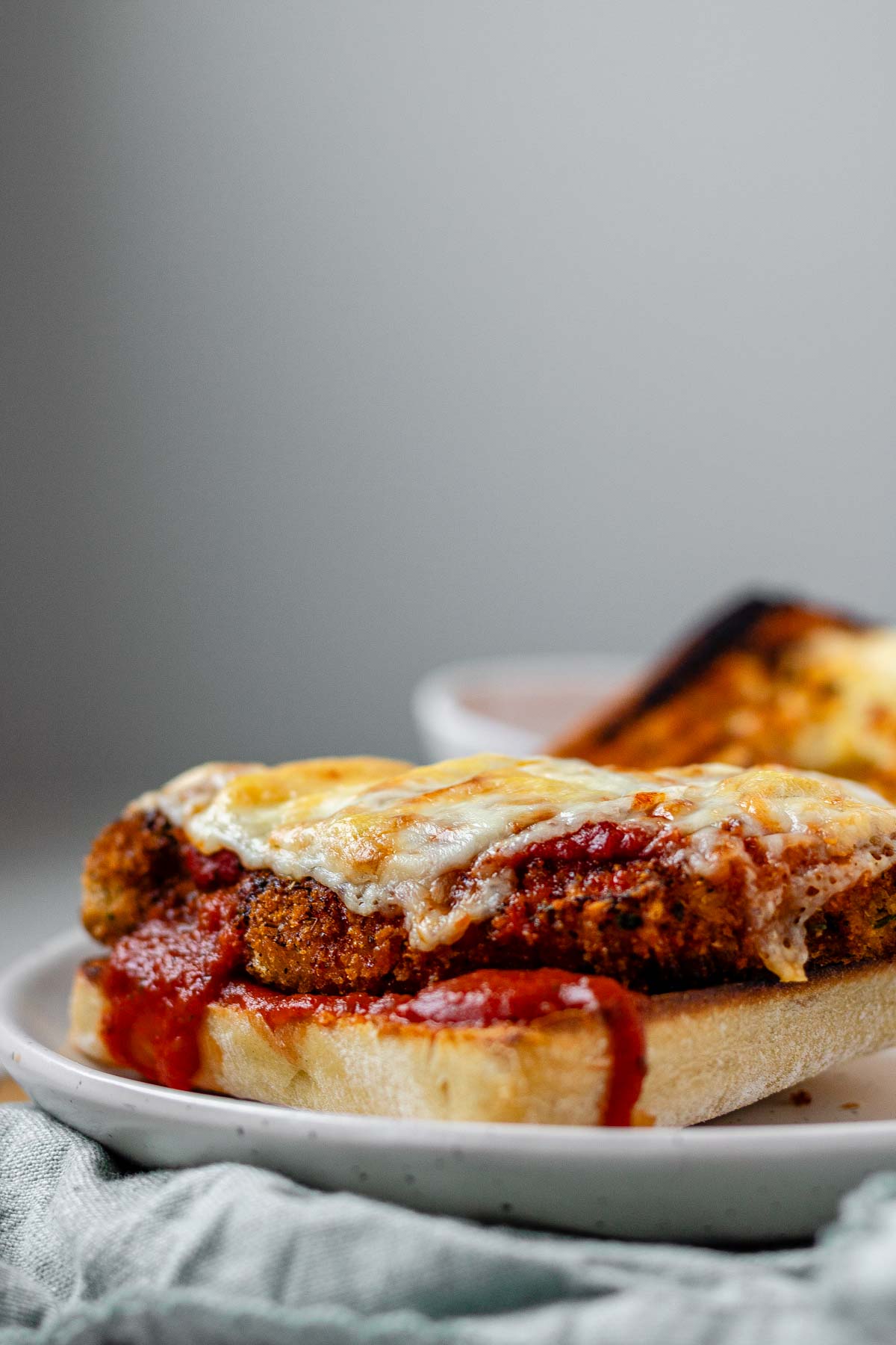 An open sandwich with breaded chicken, red sauce, and melted cheese.
