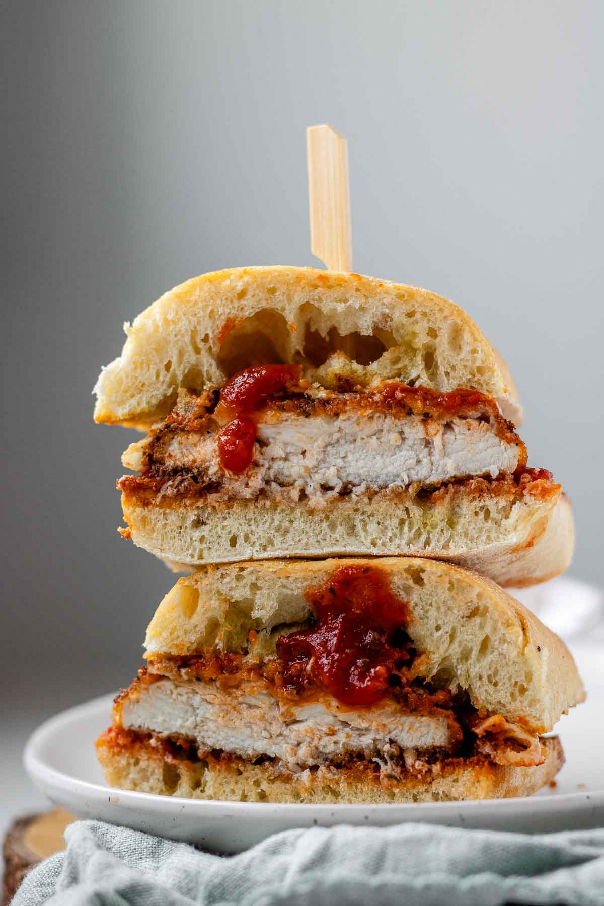 A stacked, halved sandwich with breaded chicken, red sauce, and melted cheese.