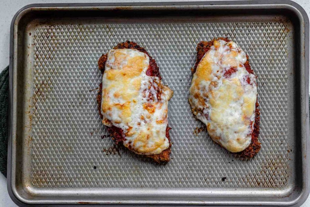 Fried chicken coated in breadcrumbs, topped with red sauce, and melted cheese.