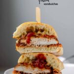 A stacked, halved sandwich with breaded chicken, red sauce, and melted cheese.