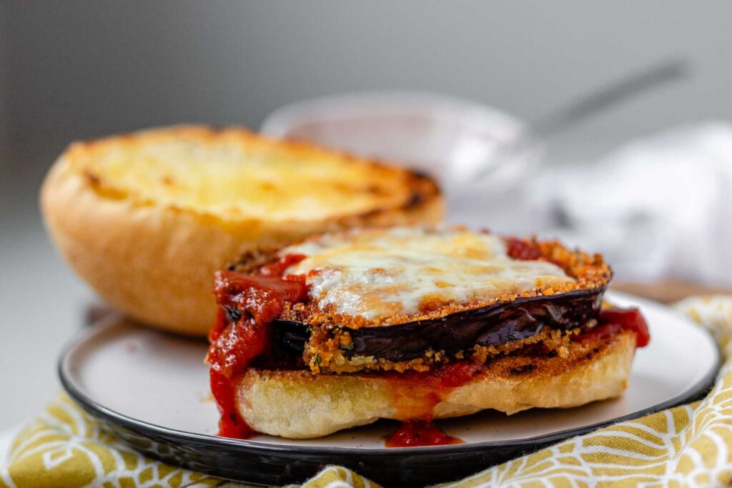 An open sandwich with a slice of eggplant and tomato sauce.
