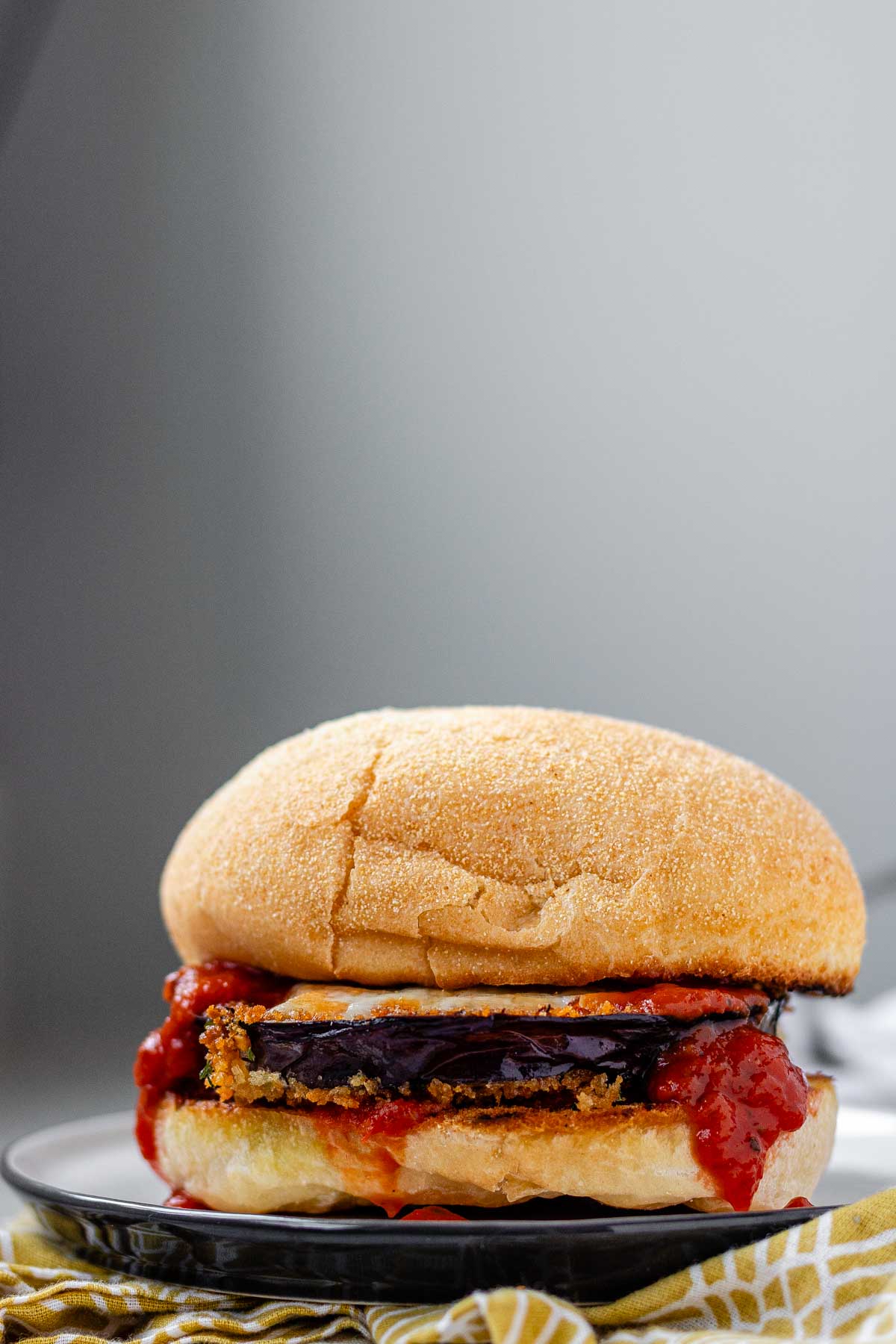 A sandwich with a slice of eggplant and tomato sauce.