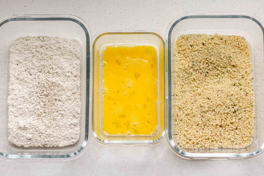 3 dishes, one with flour, one with egg, and one with breadcrumbs.