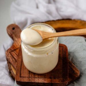 Sauce in a jar with a spoon of sauce resting on top of the jar.