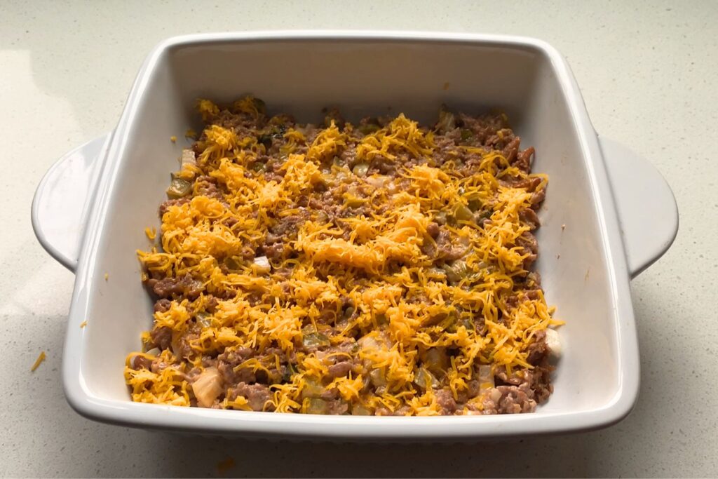 Beef topped with cheese in a white baking dish.