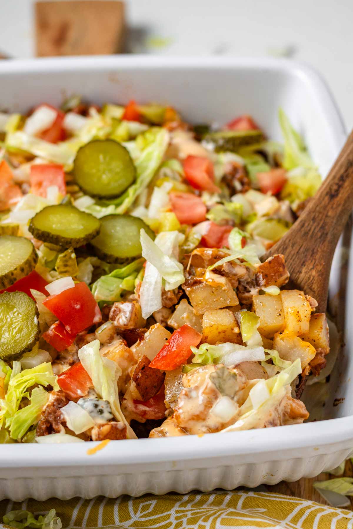 Big Mac casserole in a white casserole dish with a wooden spoon.