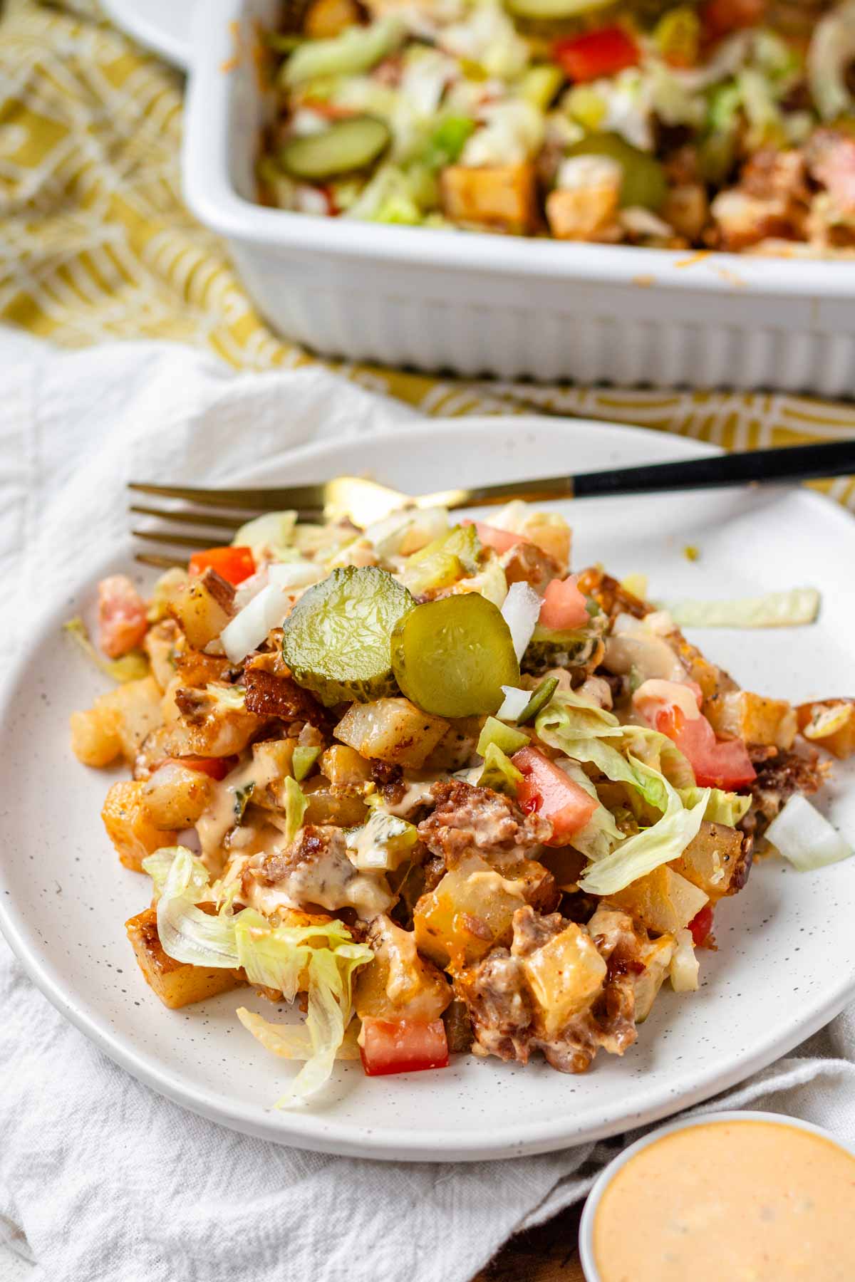 A plate of Big Mac casserole topped with pickle slices.