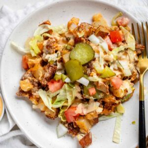 A plate of Big Mac casserole topped with pickle slices.