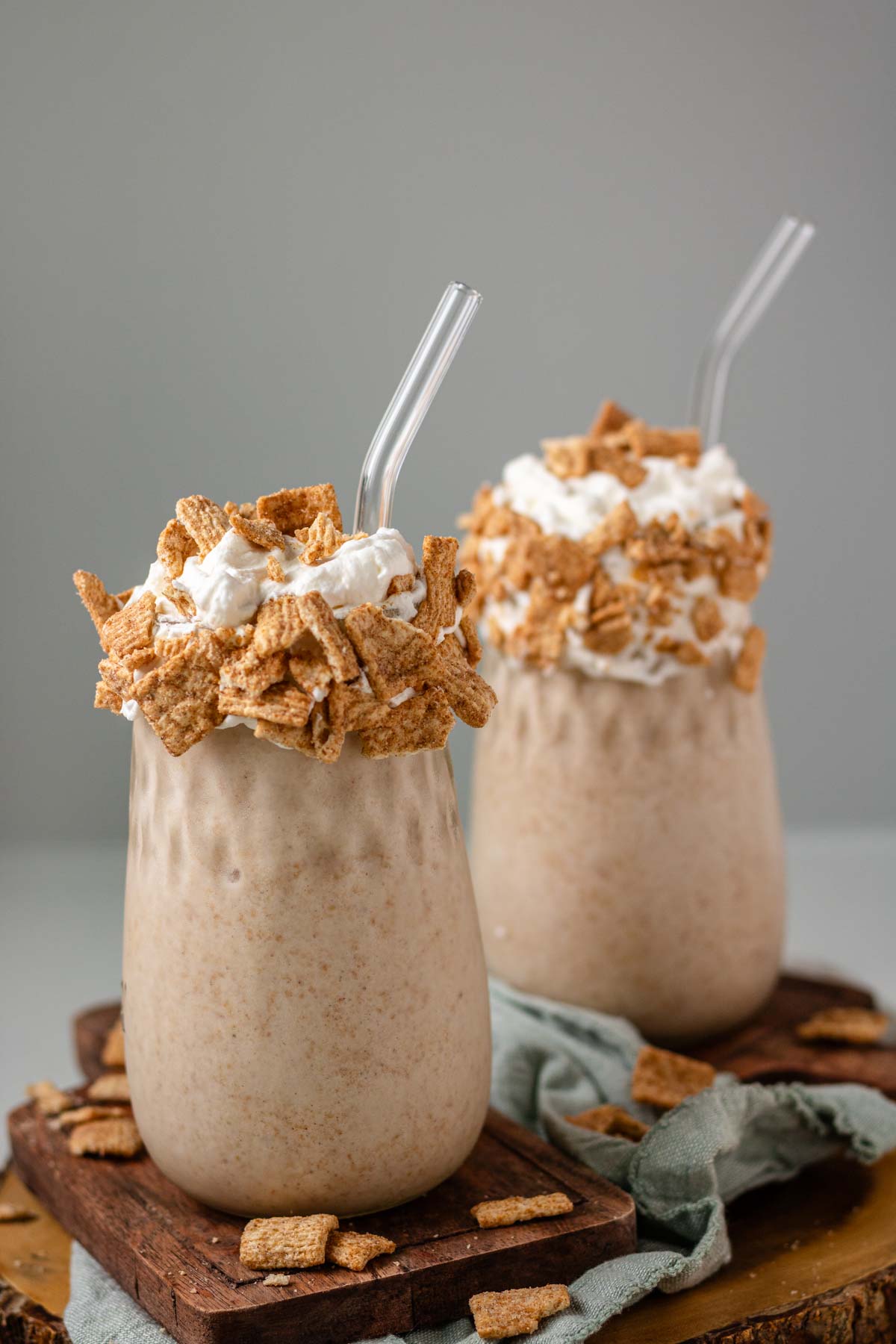 Two milkshakes topped with whipped cream and cereal.