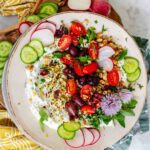 Dip on a plate garnished with fresh vegetables and herbs.