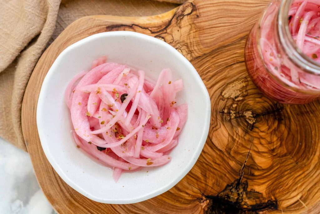 Pickled red onions in a bowl and a jar.