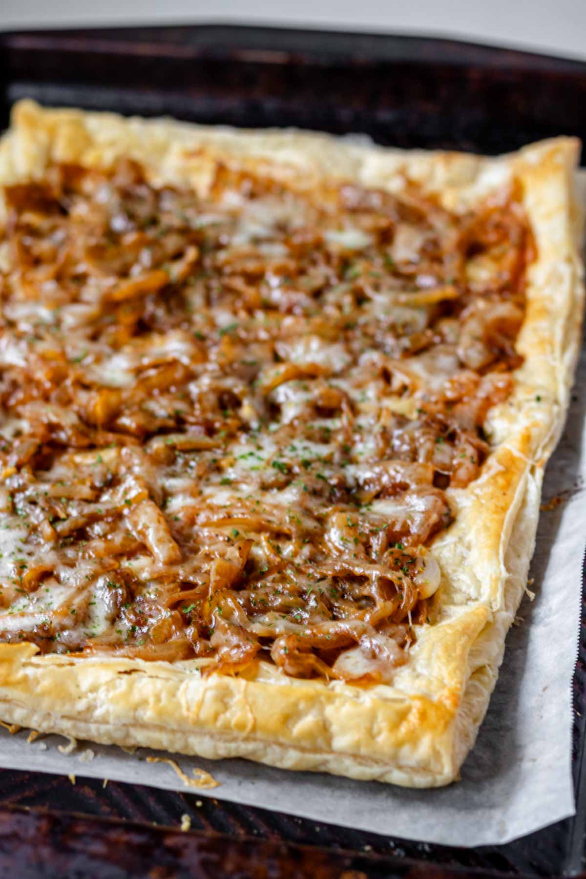 A close up of caramelized onions and melted cheese on top of puff pastry.