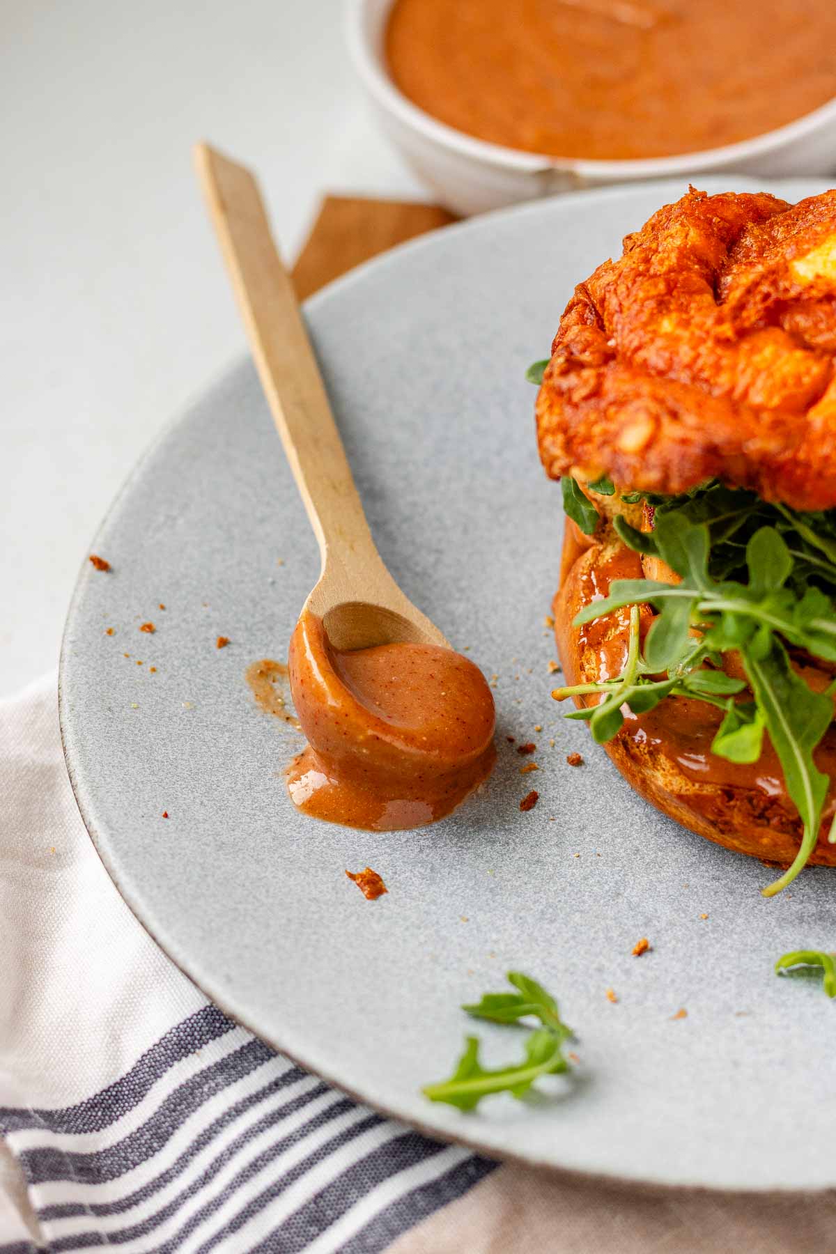 Bbq mayo on a spoon on a plate beside a burger.