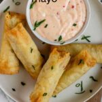 Sweet chili mayo in a bowl on a plate beside spring rolls with the text sweet chili mayo.