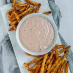 Sauce in a bowl beside french fries.