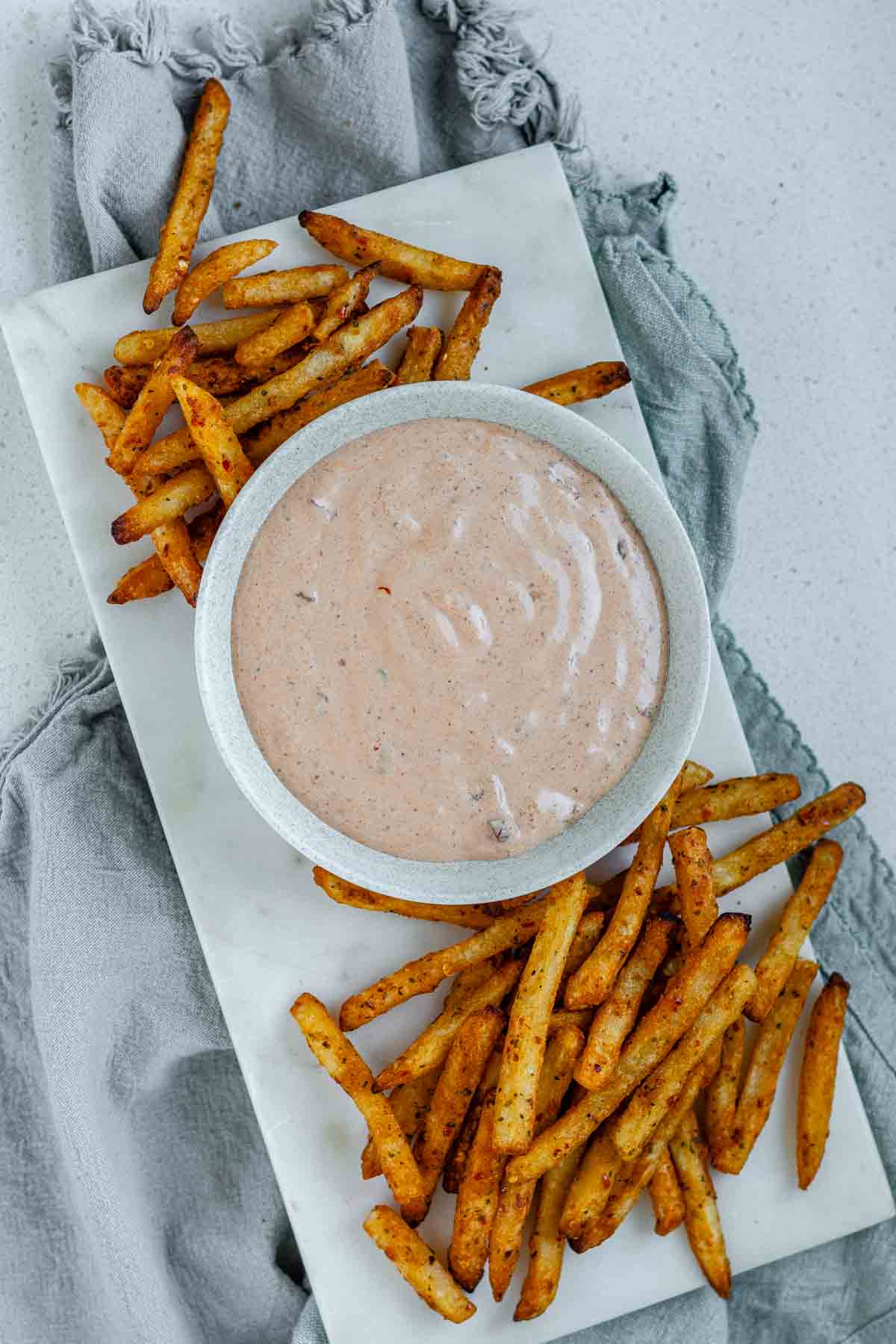 Sauce in a bowl beside french fries.