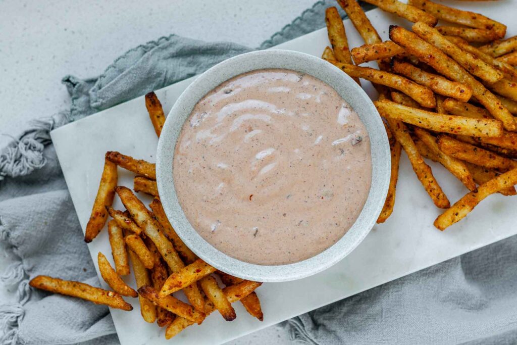Sauce in a bowl beside french fries.