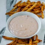 Sauce in a bowl beside french fries.