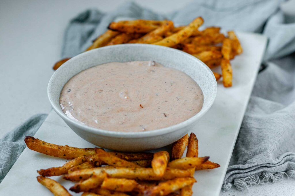 Sauce in a bowl beside french fries.