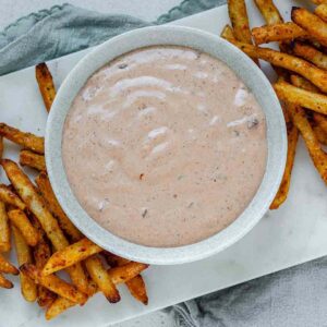 Sauce in a bowl beside french fries.