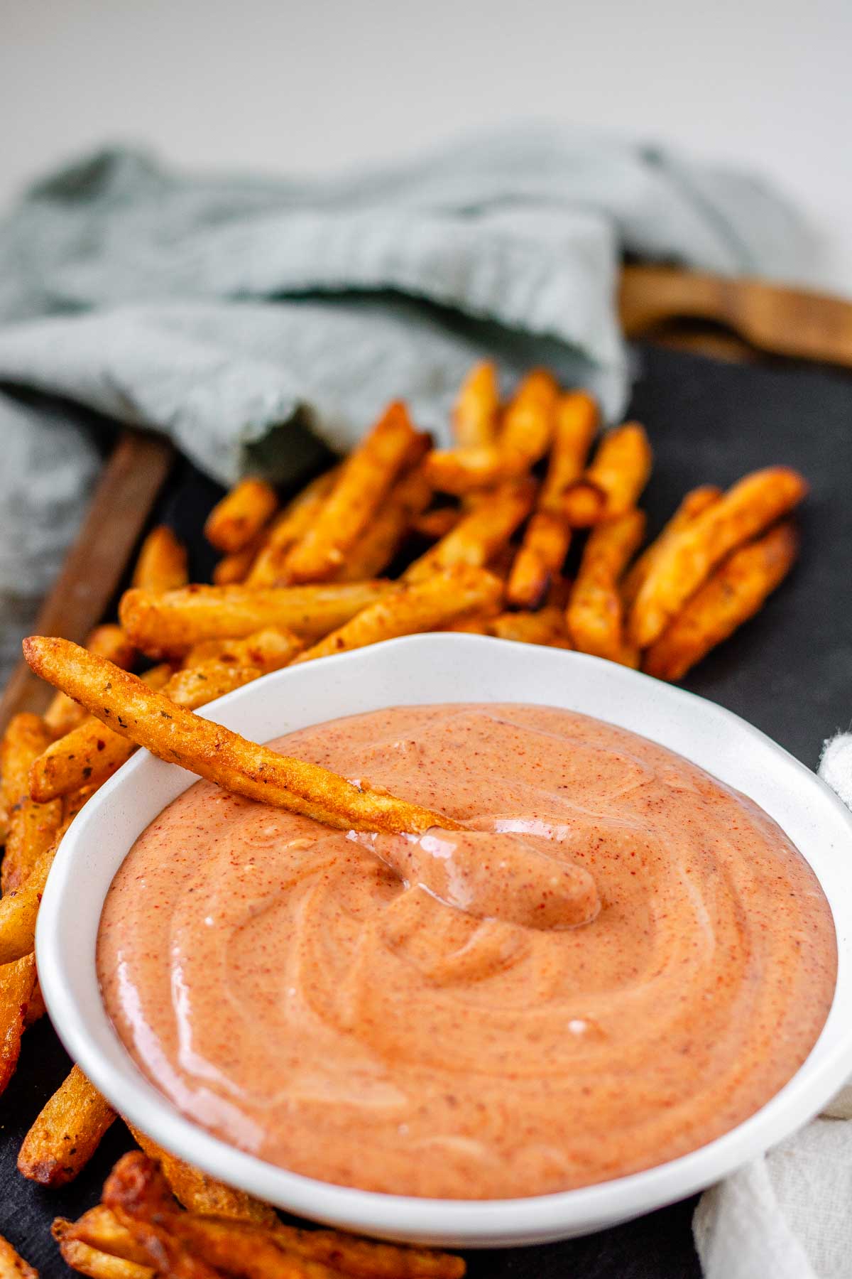 Orange sauce in a bowl surrounded by fries.
