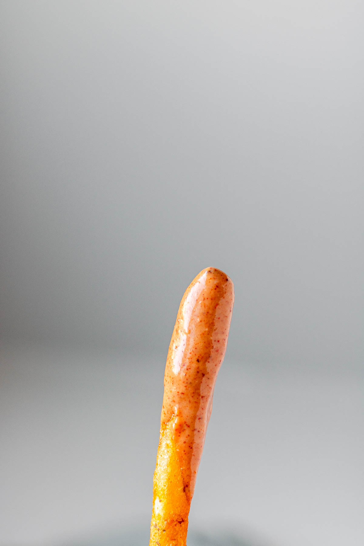 A French fry with sauce on it.