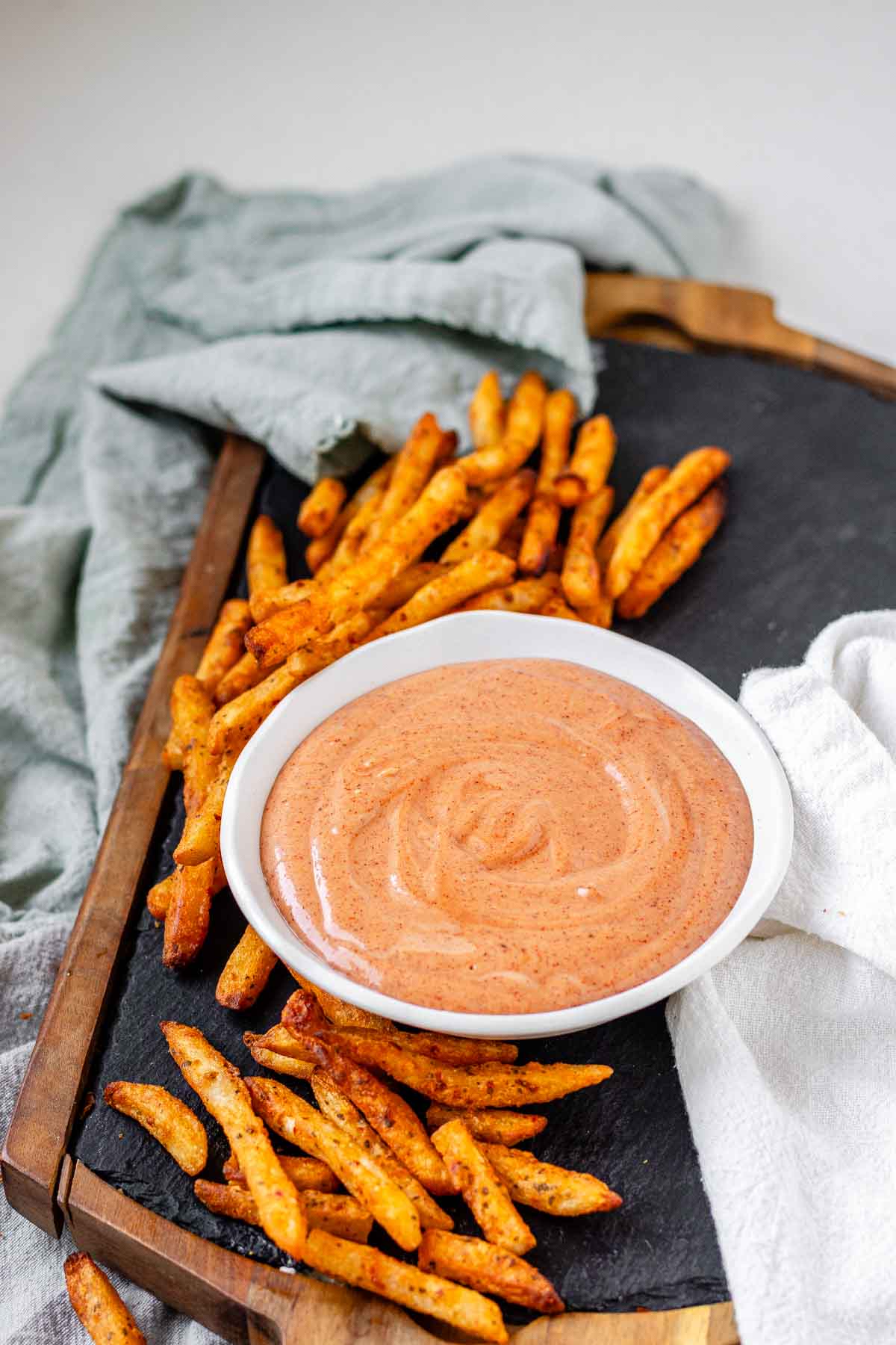 Orange sauce in a bowl surrounded by fries.