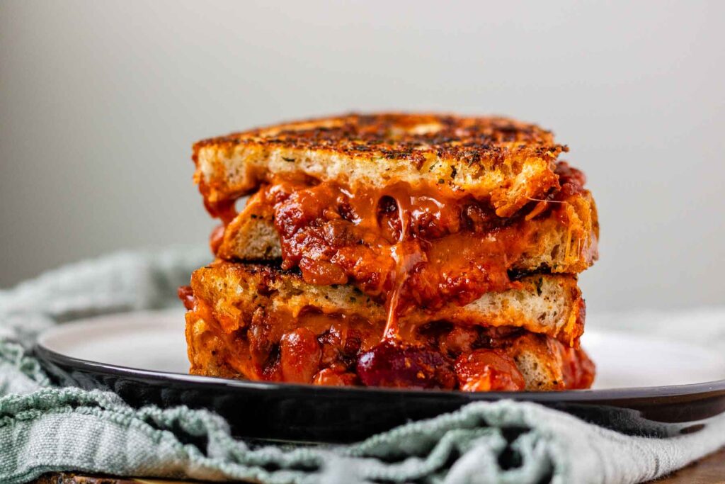 A grilled cheese sandwich with chili oozing out.